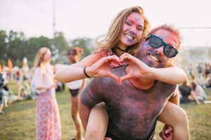 Beautiful couple covered in colorful powder having fun at summer holi festival