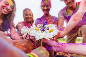 cropped shot of young friends holding chamomiles at holi festival