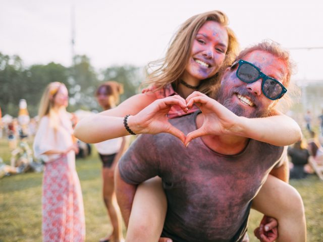 Beautiful couple covered in colorful powder having fun at summer holi festival